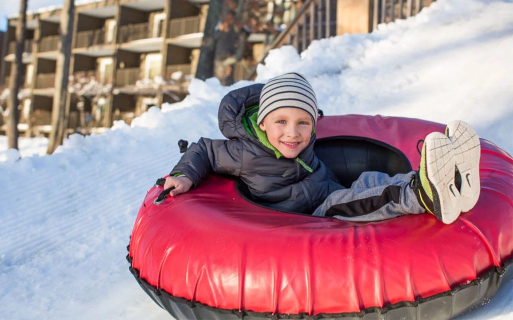 Young boy riding red sno-tube at Woodloch Resort