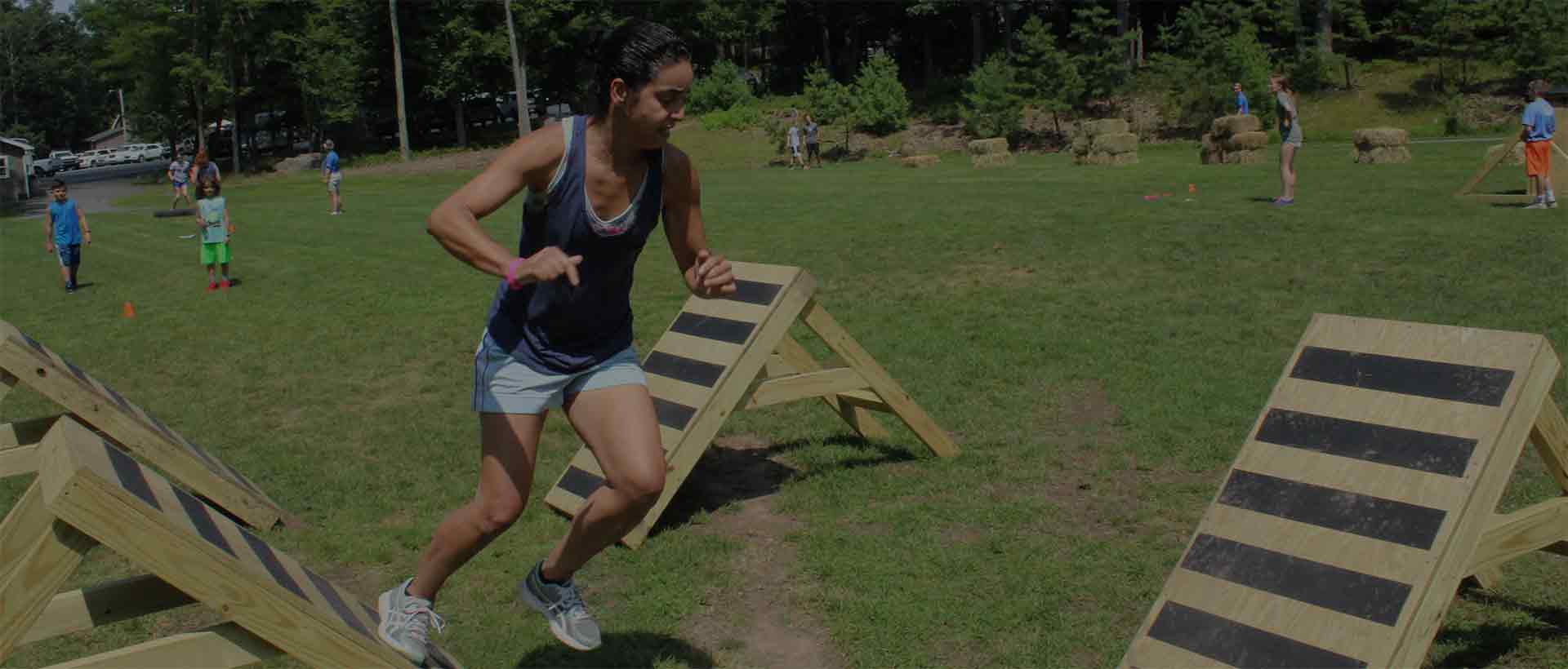 Image of woman racing through our Amazing Race obstacle course at Woodloch Resort