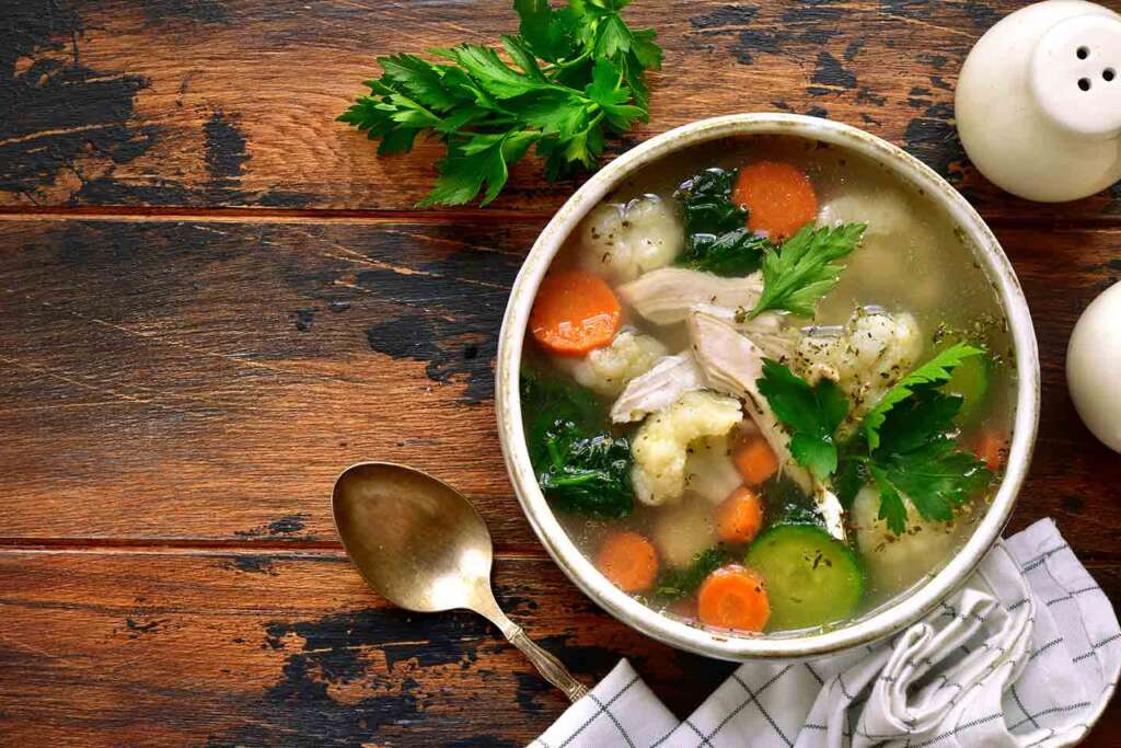 Photo of bowl of chicken soup on rustic table